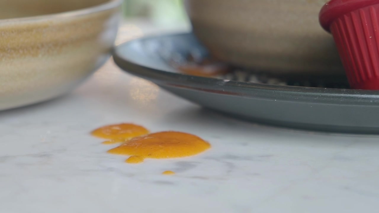 Close-up of Spilled Orange Sauce on a White Table