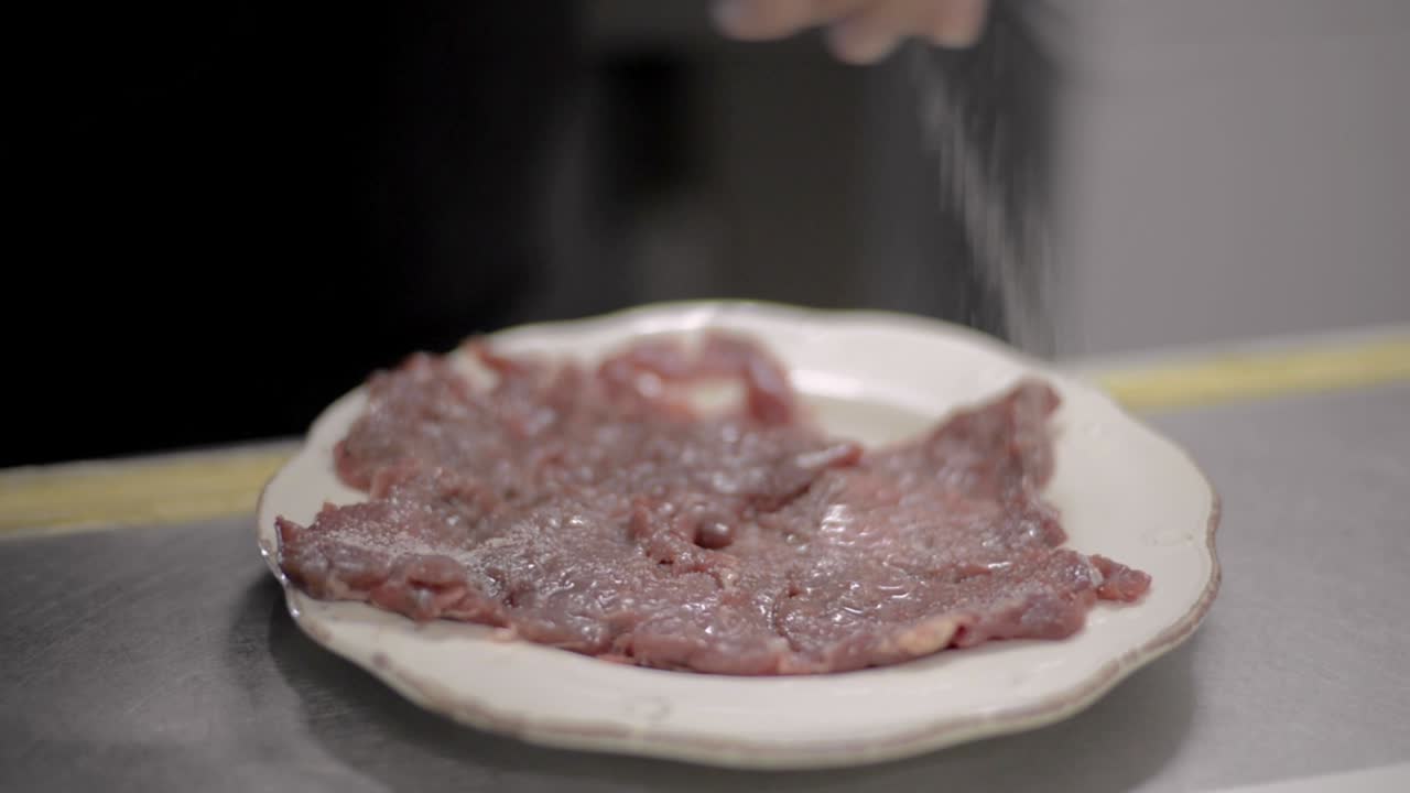 Close up of a Man Chef cook salting seasoning meat steak on a white plate at a local diner cafe restaurant in Mexico Latin america
