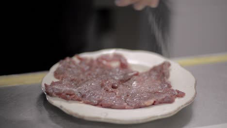 close up of a man chef cook salting seasoning meat steak on a white plate at a local diner cafe restaurant in mexico latin america