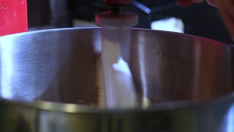 Close-up-of-egg-being-cracked-on-edge-of-stand-mixing-bowl-to-add-to-recipe