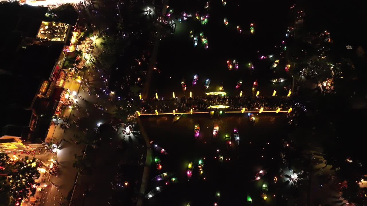 Colorful boats and festive crowds gather at night in Hoi An, Vietnam for a celebration