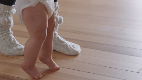 close up feet baby learning to walk toddler taking first steps with parent helping infant teaching child at home