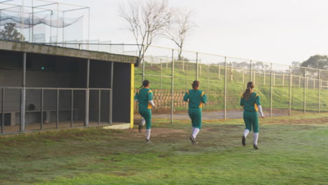 multiracial female baseball players warming up, doing sidestepping and running on a pitch