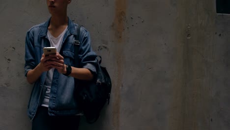 man using mobile phone while leaning against wall 4k