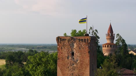 flag waving in the wind on tower of rivalta castle, piacenza in italy