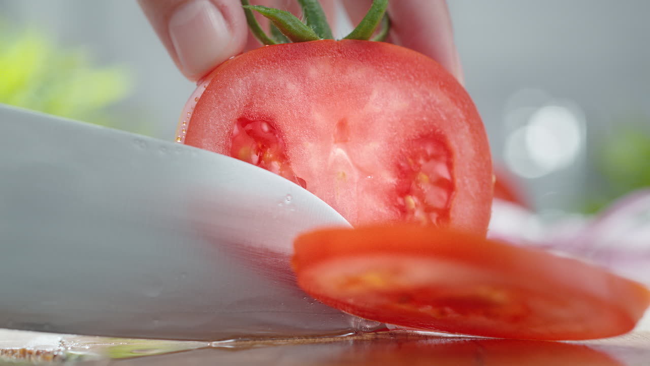 한 주방 칼로 토마토 조각을 나무로 된 물로 인 절단판, 거시 및 느린 동작으로 절단합니다.