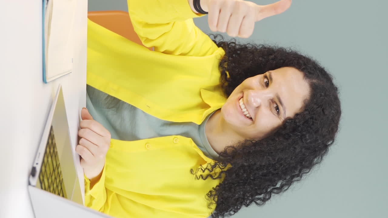 Video verticale di giovane donna che guarda il laptop mentre fa un gesto positivo