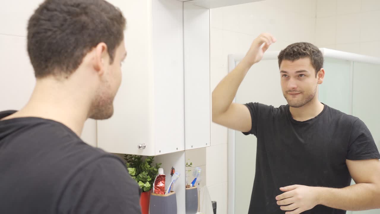 거울 앞에서 머리카락을 곧게 하는 남자는 자신을 예 ⁇ 다고 생각합니다.