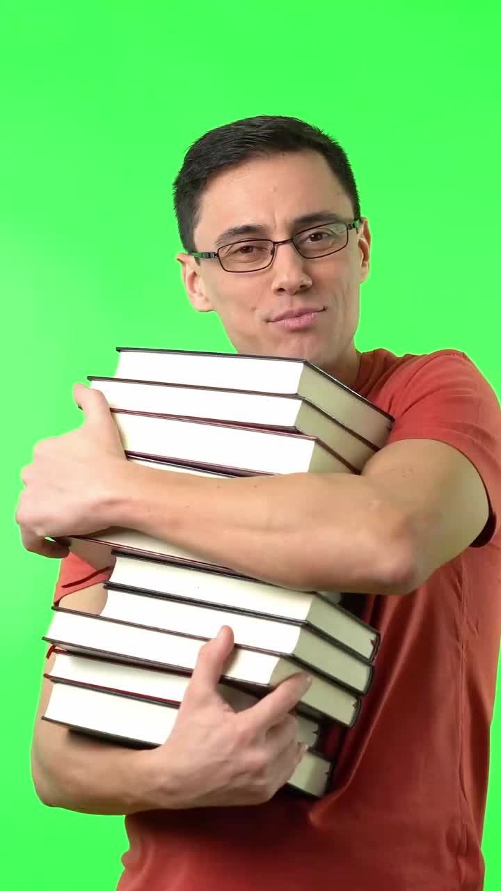 Man hugging a stack of books on a green screen