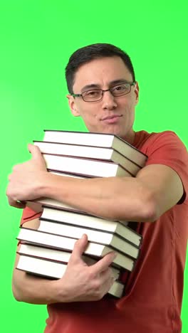 man hugging a stack of books on a green screen