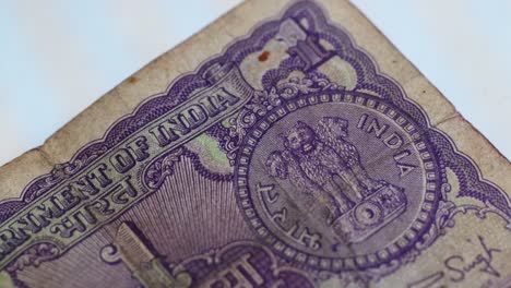 close-up of vintage indian 1 rupee note with indian national emblem and finance ministry manmohan singh signature. internal shot, tilt up shot, 4k.