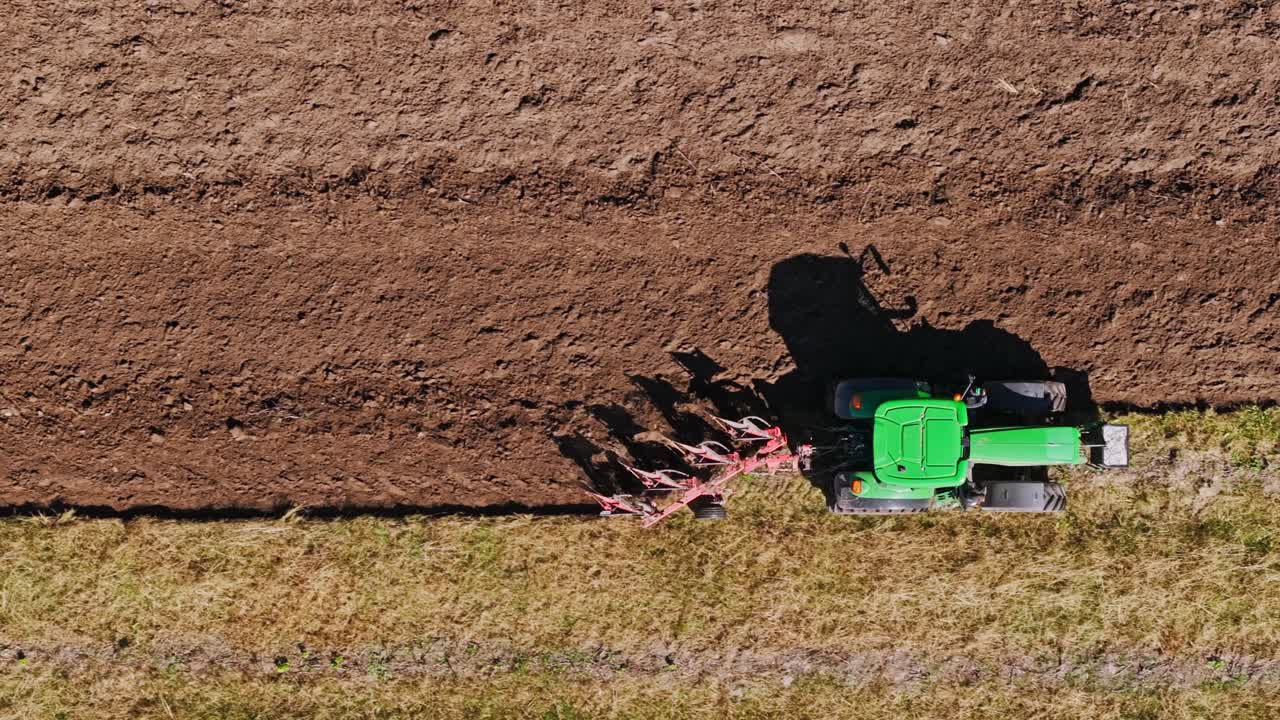 Drone top view of tractor plowing farmland highlighting climate change symbolism