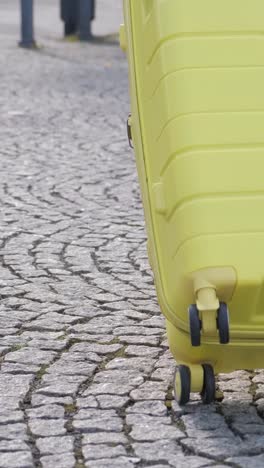 slow motion of a female tourist in a fashionable outfit walking down a european street and carrying her bright yellow wheeled suitcase. vacation and travel