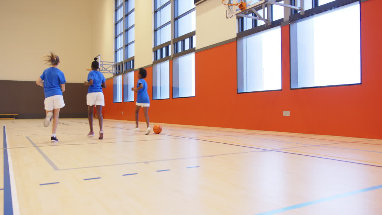 Basketbal spelen in de schoolgymzaal, drie kinderen rennen naar de basket, met ruimte voor tekst.