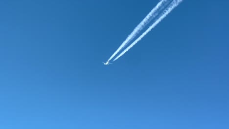 pilot pov of a white color jet flying across a blue sky with its wake clearly visible