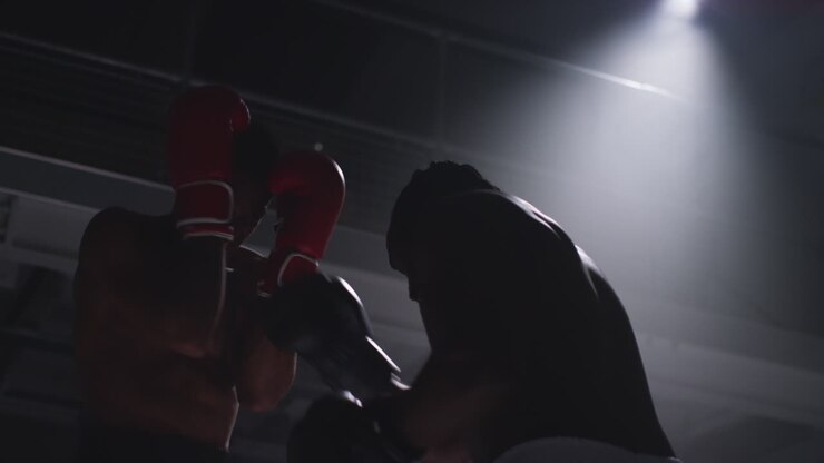 Close Up Shot Of Two Male Boxers Wearing Gloves In Boxing Ring Fighting In Boxing Match With Low Key Lighting 7