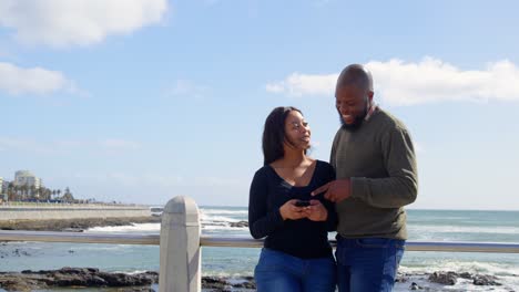 Pareja-Feliz-Usando-Teléfono-Móvil-Cerca-De-La-Barandilla-En-Un-Día-Soleado-4k