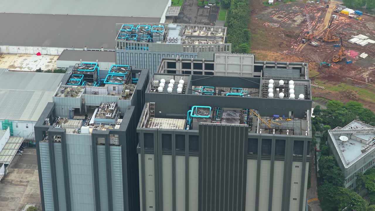 Optagelse i høj vinkel af en moderne datacenterbygning med dens omfattende køle- og ventilationssystemer på taget i et industriområde i Jakarta, Indonesien.