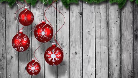Animation-of-christmas-baubbles-over-wooden-background