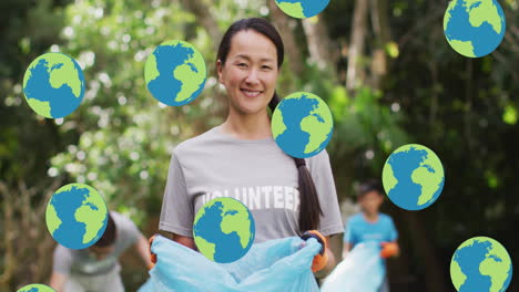 animation of falling globes over diverse group of happy people picking up rubbish in countryside