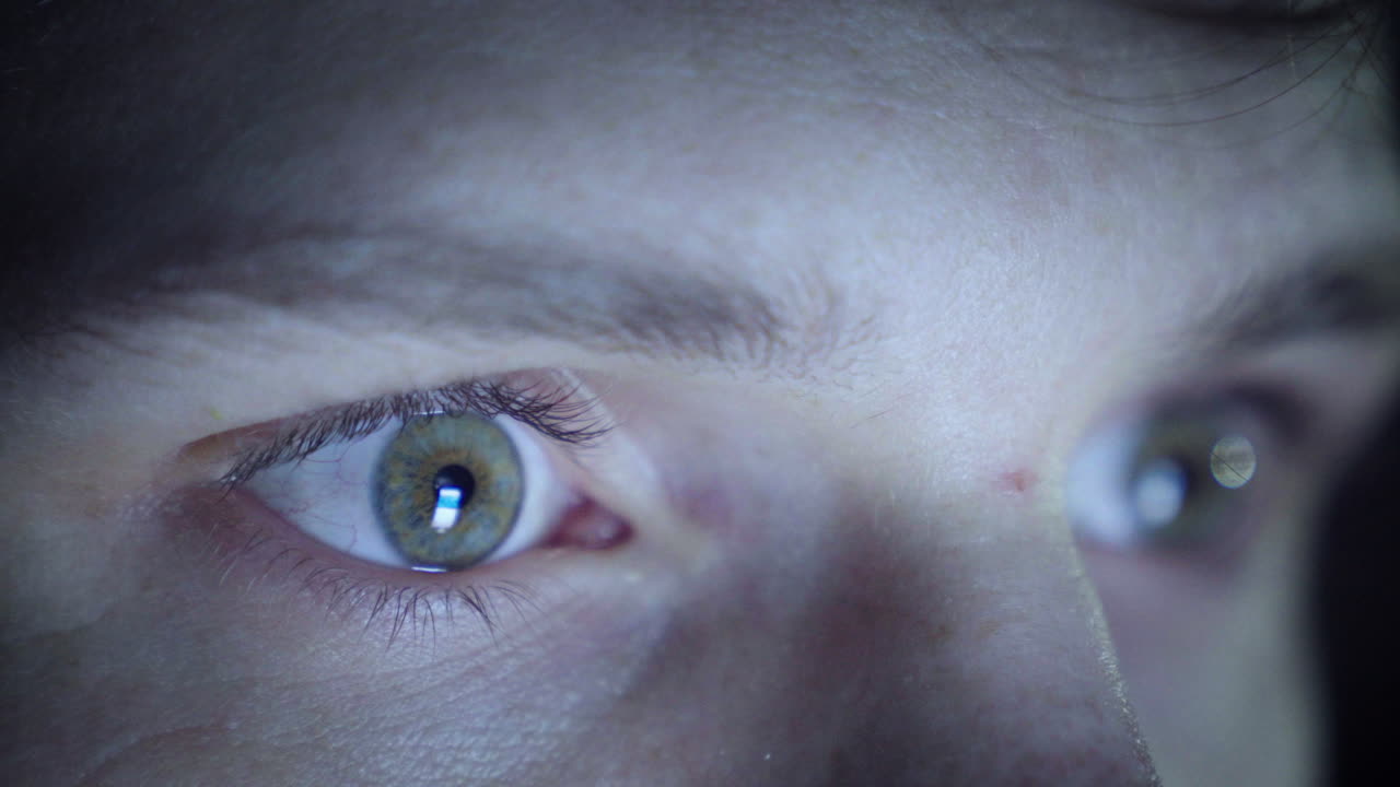 hombre desplazándose por su teléfono en un ambiente oscuro