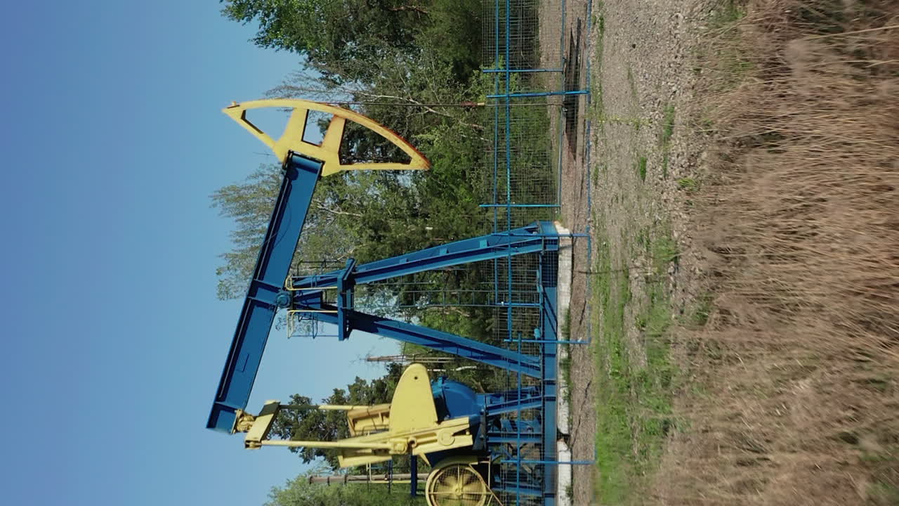 вертикальный снимок работающего нефтяного насосного станка на месторождении в светлое время суток