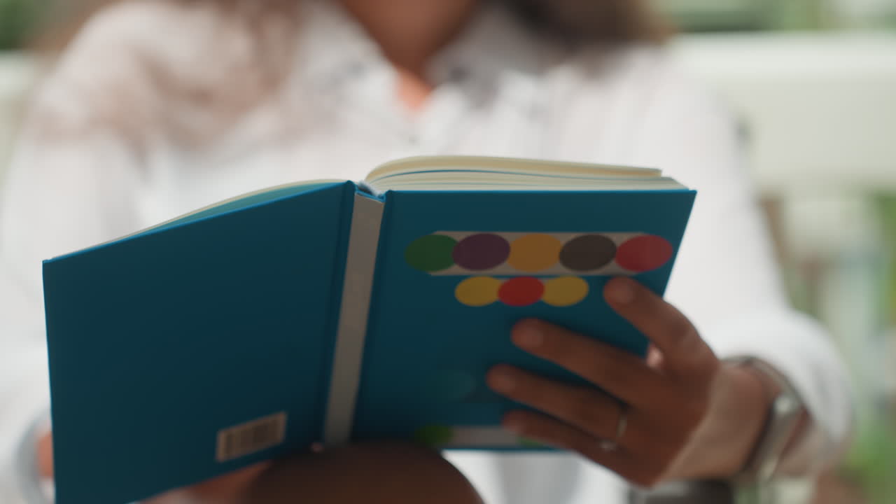 Signora che si gode un libro in riva al mare. Scena di veranda illuminata dal sole che mostra una signora sfogliare pagine vivaci di un diario. Ambiente esterno sereno dove una donna si rilassa su un portico tropicale con una rivista colorata.