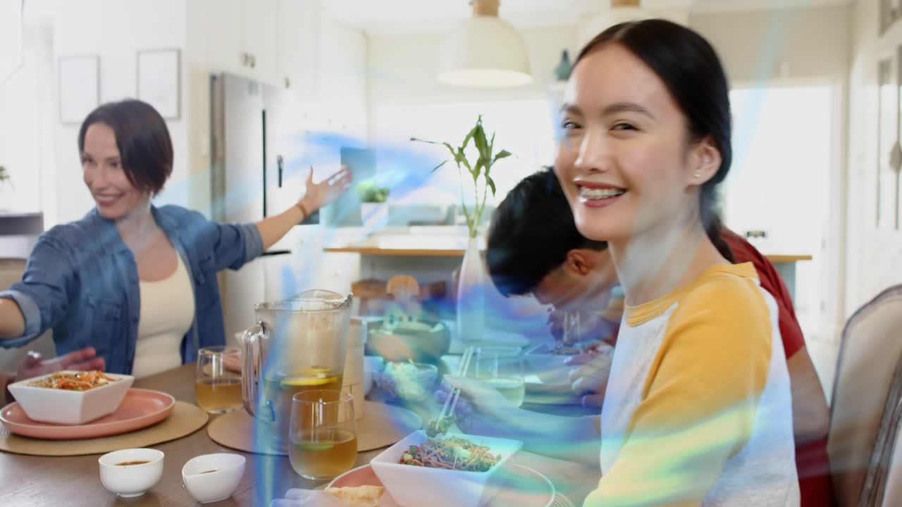 Blue swirl drifting, woman in yellow with chopsticks turning, smiling, greeting camera during food