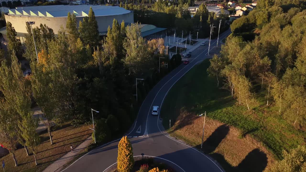 coche blanco conduciendo por una carretera secundaria poco transitada durante el aterdecer. Vista aerea 4k