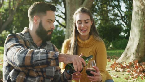 Video-of-happy-caucasian-warmly-dressed-couple-drinking-wine-in-the-garden