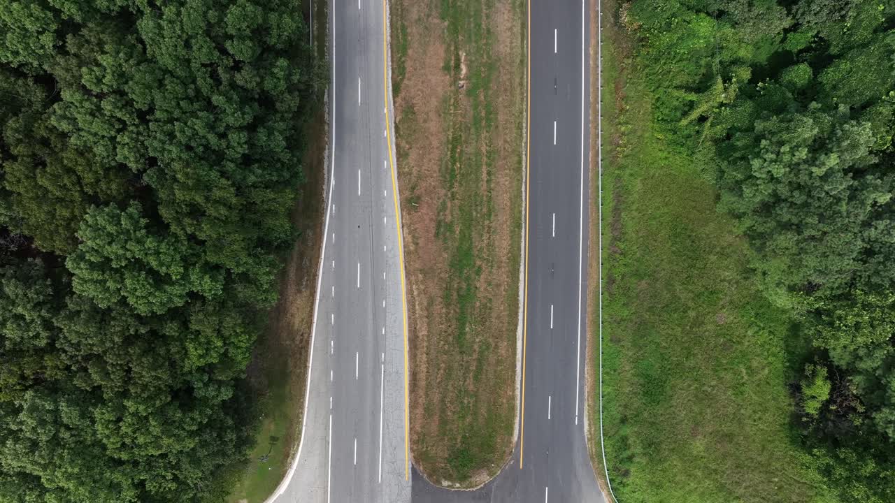 Driving car on interstate road between green trees in suburbia of American town. Aerial top down landing shot. Two separate street lines on highway in Virginia,usa