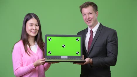 young asian woman and young businessman showing laptop together