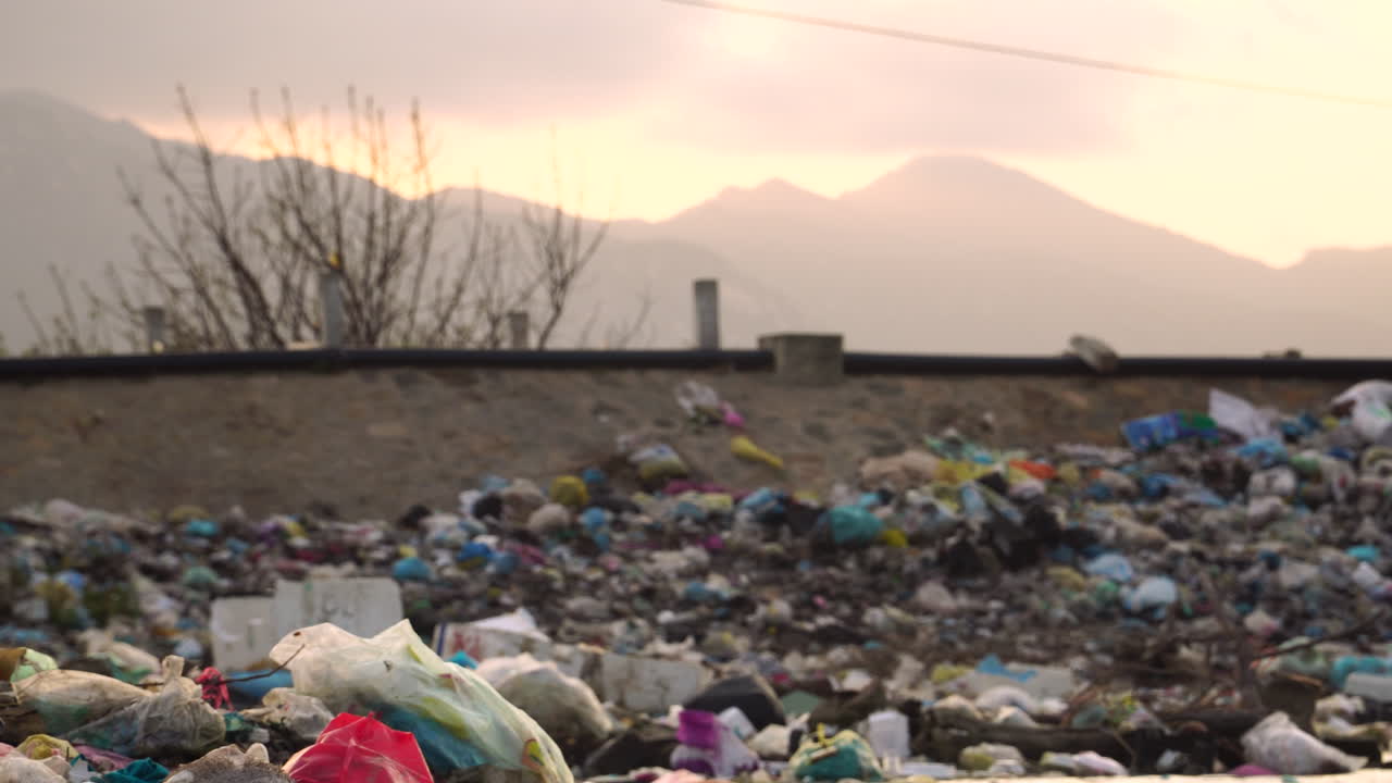 lado de la carretera lleno de basura de bolsas de plástico en el sudeste asiático, scooters conduciendo en la carretera en segundo plano
