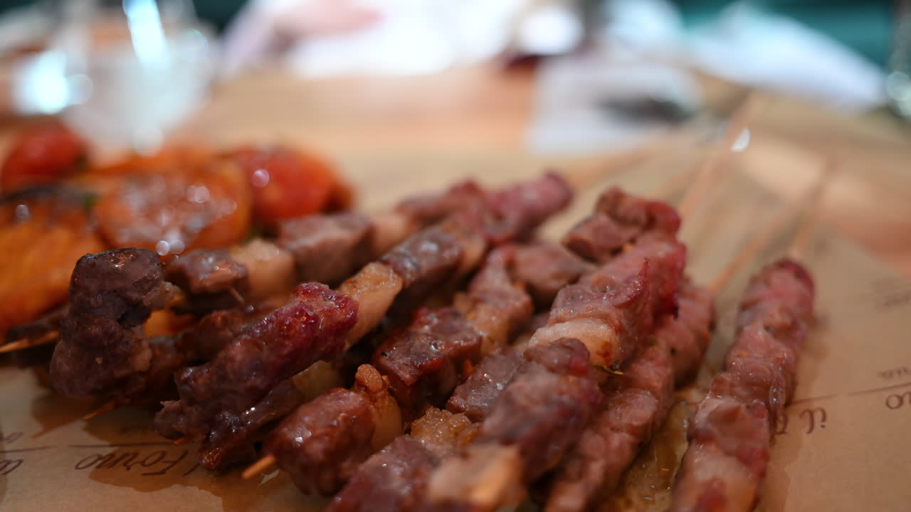 Vista dettagliata di spiedini di carne alla griglia su bastoncini di legno con profondità di campo ridotta