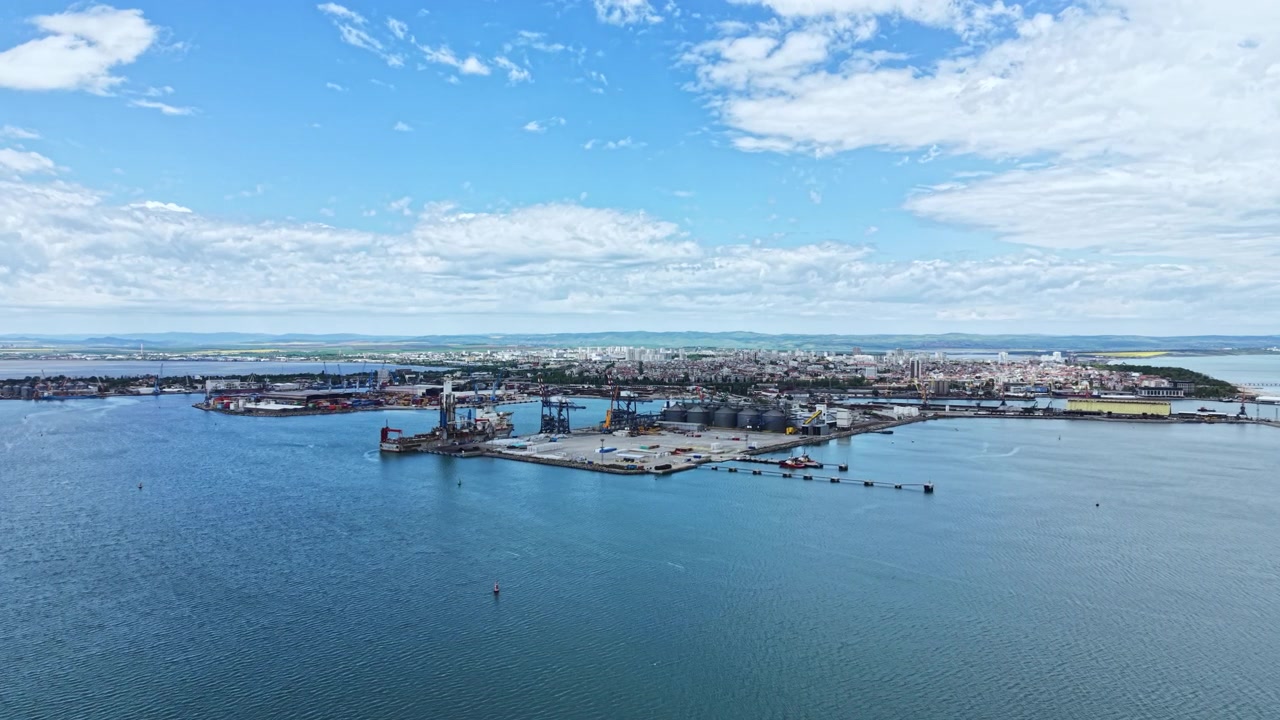 Utsikt över en stor hamn under dagen med fartyg och containrar längs strandlinjen i en kuststad