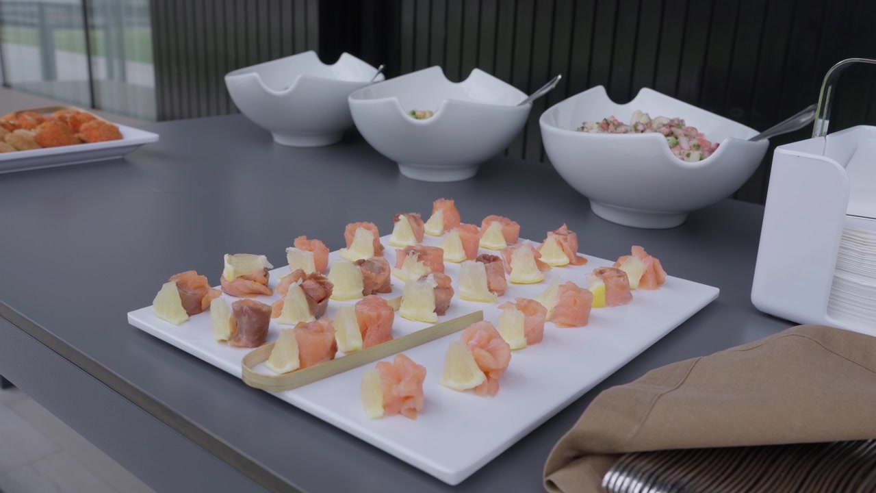 Canapés de Salmão Defumado e Queijo Dispostos em uma Bandeja Retangular com Tigelas de Salada