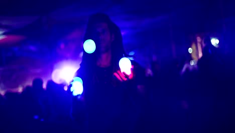 hombre haciendo malabarismos con bolas de luz durante una fiesta nocturna