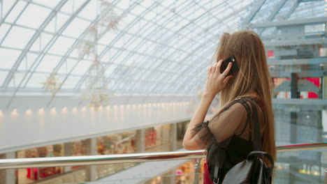 sale, consumerism: young woman with smartphones and shopping bags standing and talking near shopping centre