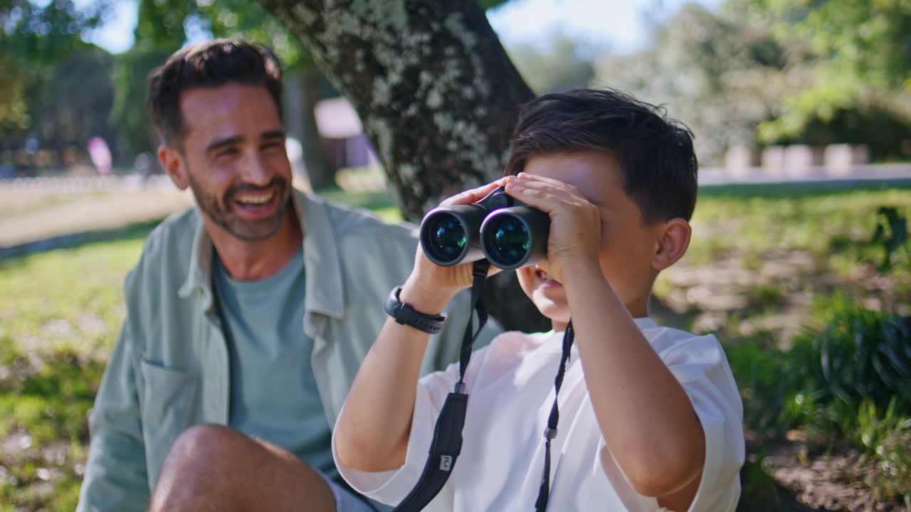 Daddy kid watching binoculars on sunny day closeup. Man enjoying birdwatching