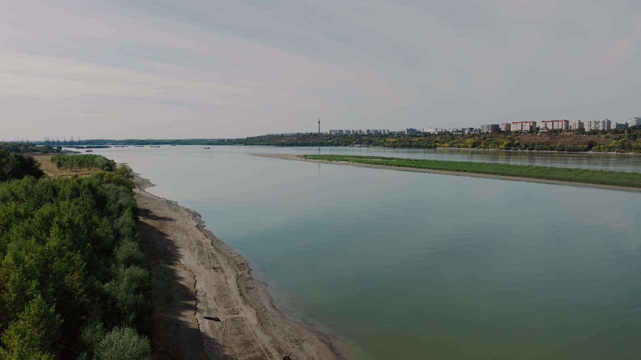 drone disparado moviéndose a lo largo de la idílica orilla del río, enmarcado por un frondoso dosel de árboles verdes