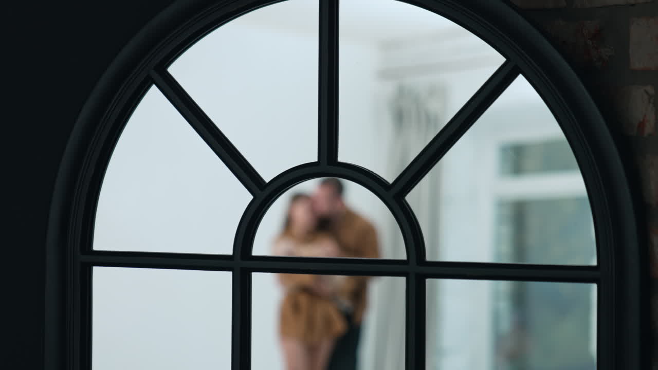 Arched top of the window. Close up. Blurred silhouette of a couple at backdrop.