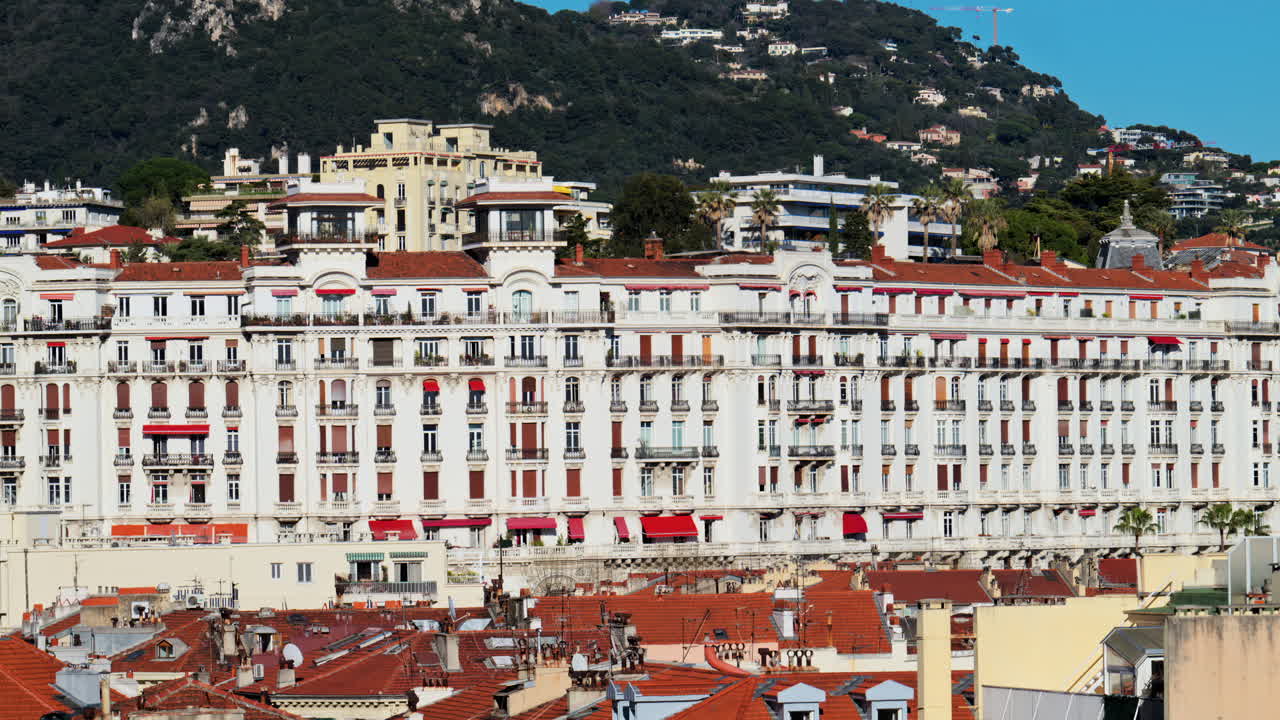 Nice, France - March 25, 2025: Distant view of the Majestic Apartment complex with the mountains on the background