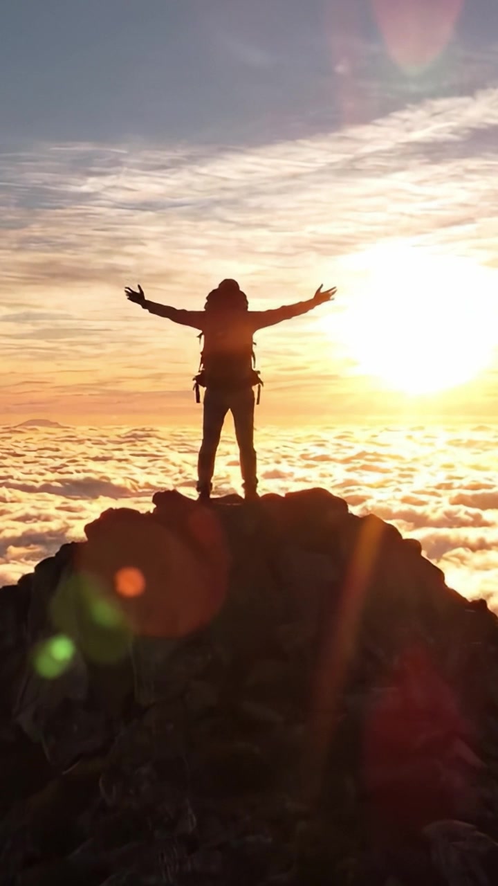 Un alpinista solitario si erge trionfante in cima a una vetta rocciosa, sagomato contro un cielo al tramonto mozzafiato pieno di nuvole, catturando l'essenza dell'avventura e dell'esplorazione tra le altezze della natura.