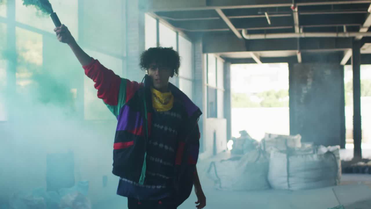 Mixed race man holding blue flare running through an empty building