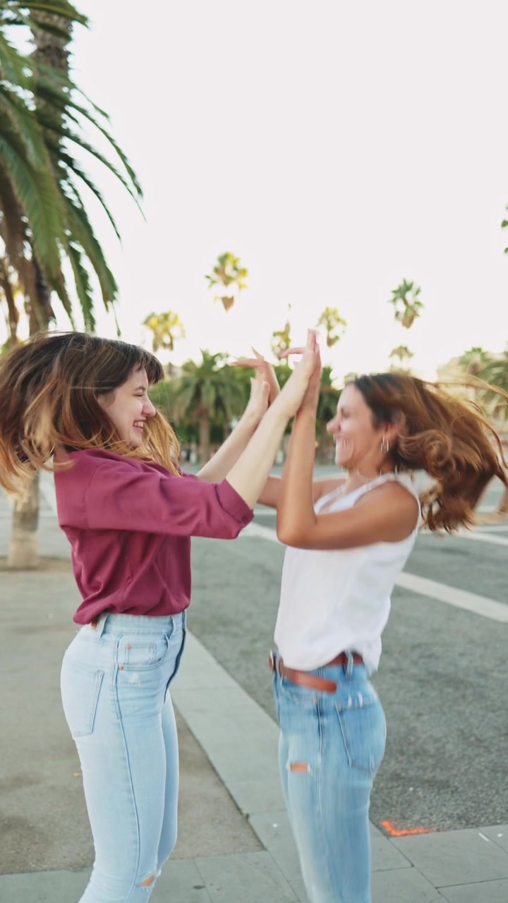 Dos mujeres felices riendo y bailando alegremente al aire libre