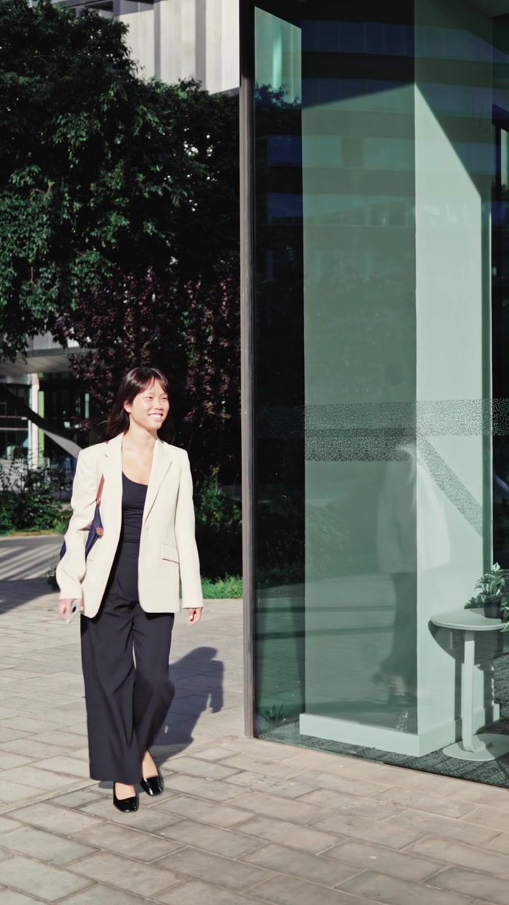 Joven empresaria feliz caminando al aire libre en una ciudad moderna