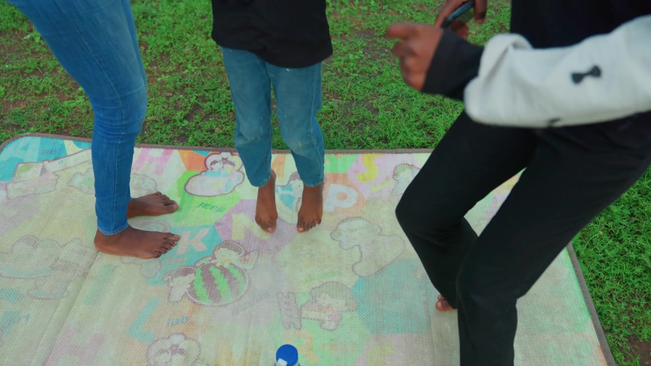 Mère enseigne pieds nus. Mère attentionnée guidant son enfant dans une cour ouverte. Moment familial calme avec mère et enfant sur l'herbe. Douce instruction pieds nus par la mère à l'enfant sur une zone herbeuse colorée.