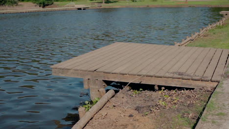 wooden deck extending over the water of a calm lake with grassy shore