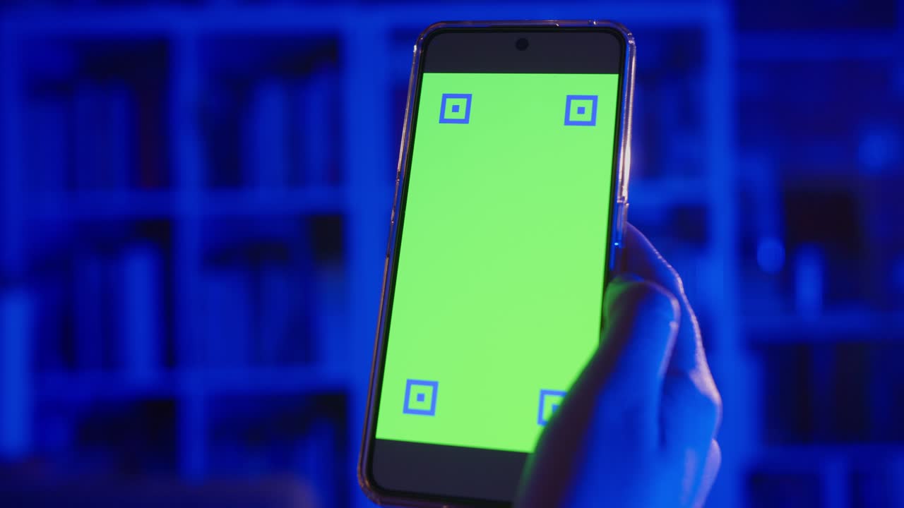 Hand Holding Smartphone with Green Screen and Tracking Markers in Blue Light