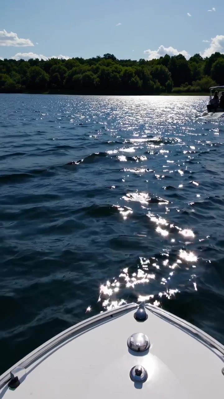Vista da una barca su un lago soleggiato con un'altra barca più avanti